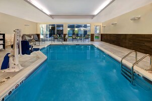 Piscina interior con un puesto de socorrista, sillas de descanso y vistas al exterior a través de amplios ventanales.