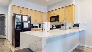 A modern kitchen with wooden cabinets, a black refrigerator, a microwave, and a sink with a stainless steel faucet. - On Sierra Star Golf Course, Washer/Dryer, Quiet Location & On-site Pool (Mammoth Lakes)