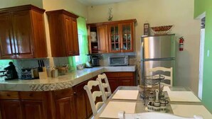 A kitchen with wooden cabinets, a stainless steel refrigerator, a microwave, and a dining table with chairs.