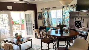 A living room with a dining table, chairs, a sofa, and a TV.