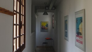 A hallway with a wooden door, a hanging light fixture, and a poster on the wall. - T3 1st floor of the villa of the sea (Hyères)