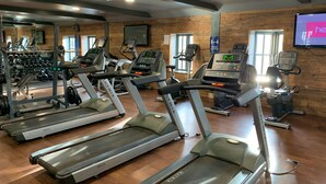 A gym with treadmills, weight machines, and a mirrored wall. - Wait n Sea -  a cottage that sleeps 4 guests  in 2 bedrooms (Filey)
