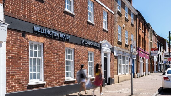 Casa Wellington, um edifício de tijolos com janelas emolduradas de branco e uma placa preta sobre a entrada.