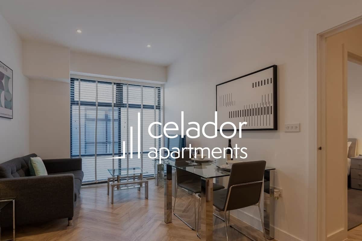 Un apartamento moderno con comedor, un sofá y un ventanal grande.