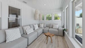 Una sala de estar moderna con un sofá seccional, una mesa de centro de madera y un ventanal con vistas al exterior.