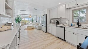 Una cocina moderna con armarios blancos, una isla grande y un comedor con vistas.