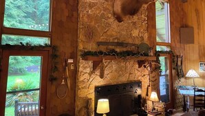Un interior rústico con chimenea de piedra, vigas de madera y una decoración de cabeza de venado.
