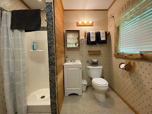A compact bathroom with a shower, toilet, and sink.