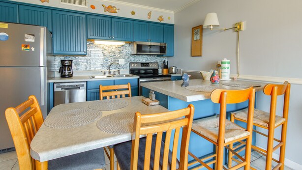Una cocina con armarios azules, un refrigerador, un microondas y una cafetera.