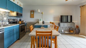 Una cocina con armarios azules, microondas, estufa y una mesa de comedor con sillas.