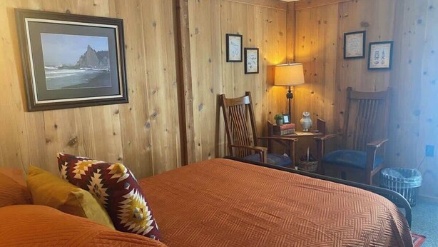 Une chambre d’hôtel avec un grand lit, une chaise, une petite table et une lampe.