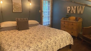 A bedroom with a bed, dresser, and a door with blinds. - Lady Lodge Room near Olympic National Park (Forks)