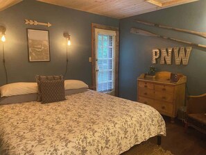 Een slaapkamer met een bed, een kapstok en een deur voorzien van jaloezieën.