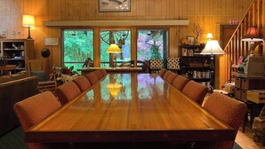 A large wooden conference table surrounded by cushioned chairs in a room with wooden walls and large windows.