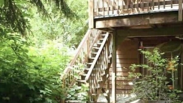 A wooden deck with two lounge chairs, a stone pathway, and a staircase leading to a covered area with chairs. - Lily Lodge Room near Olympic National Park (Forks)