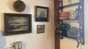 A wall with framed artwork, a decorative shelf with items, and a power outlet. - Outback Rustic Cabin near Olympic National Park (Forks)