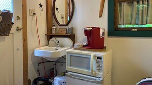 A compact bathroom with a sink, a mirror, a microwave, and a coffee maker. - Outback Rustic Cabin near Olympic National Park (Forks)