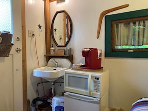Une petite salle de bain équipée d’un lavabo, d’un miroir, d’un four à micro-ondes et d’une machine à café.