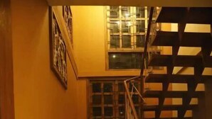 A wooden staircase with a handrail, leading to a landing with a window. - Rustic Charm Wayanad - Barefoot Bungalow (Appapara)