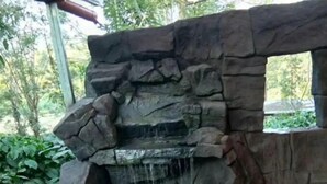 A stone water feature with a cascading waterfall into a rectangular pool. - Rustic Charm Wayanad - Barefoot Bungalow (Appapara)