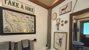 Een badkamer met een kaart, een wastafel, handdoeken en hertenhoorns aan de muur.