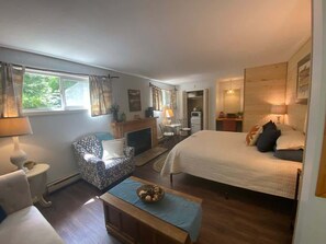 Een gezellige slaapkamer met een groot bed, een stoel, een klein tafeltje en een bureau met een lamp.