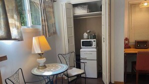 A cozy room with a dining table, chairs, a lamp, a microwave, and a closet with a cat.