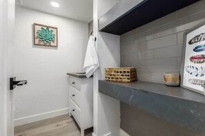 Un bagno moderno con un mobile lavabo bianco, un cesto, un quadro incorniciato e un asciugamano appeso al muro.