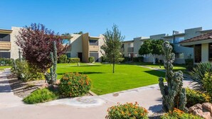 Un complejo residencial con varios edificios, un césped cuidado y diversas plantas de desierto.