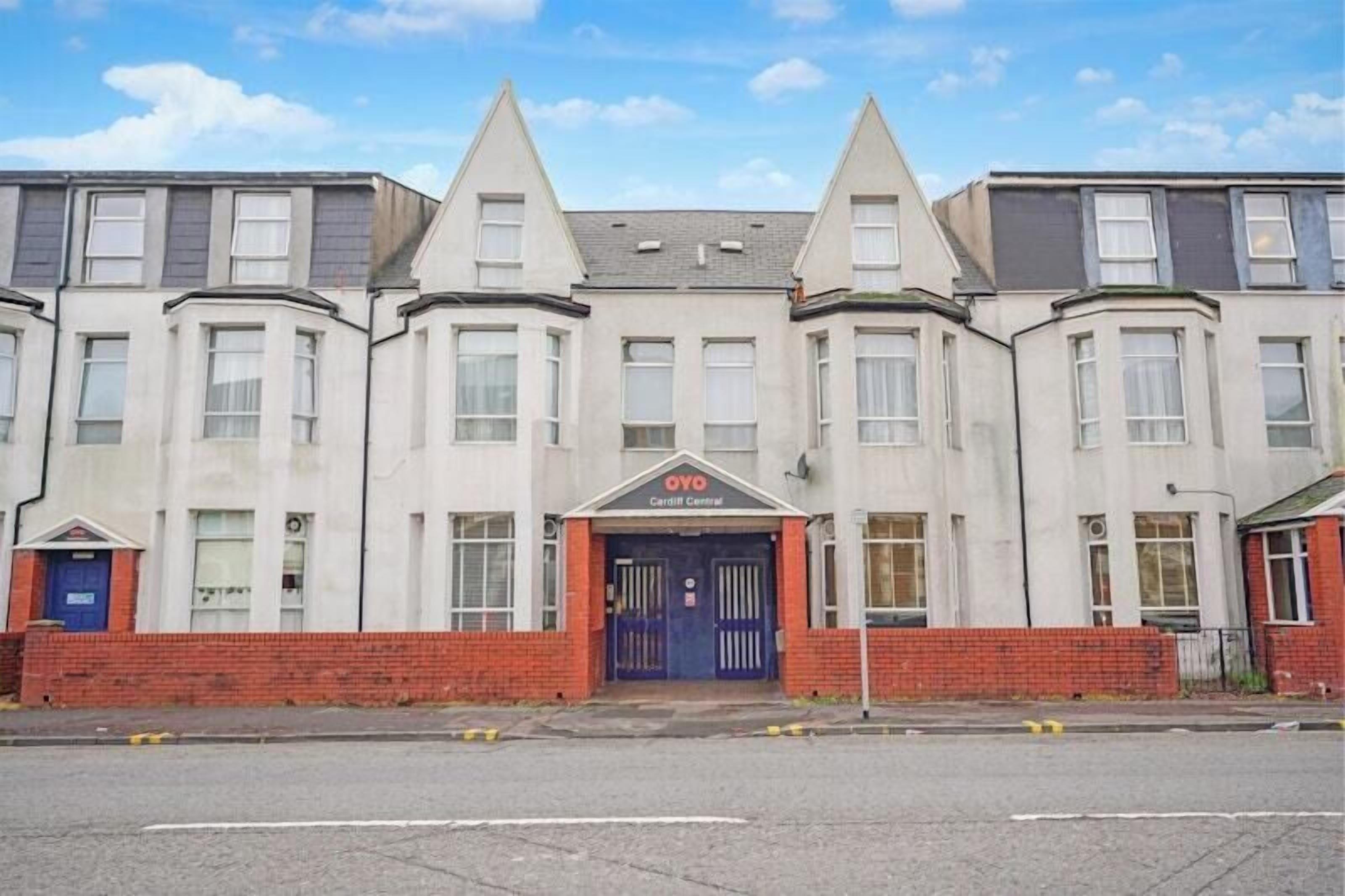 A row of terraced houses with a central entrance marked by a blue door and a sign above it.