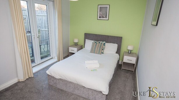 A bedroom with a bed, two bedside tables, a nightstand, a window with curtains, and a wall-mounted picture. - 6 X APARTMENTS IN 1 BLOCK JUST OUTSIDE THE CITY ⭐MINUTES WALK FROM SHOPS⭐ APT#4 (Newcastle Upon Tyne)