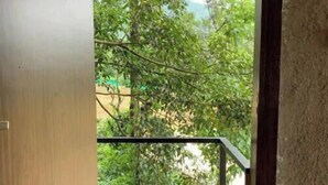 A view from a room through an open door to a balcony with a metal railing, a brown doormat, and greenery outside. - Rustic Charm Wayanad - The Stump (Treetop Suite) (Appapara)