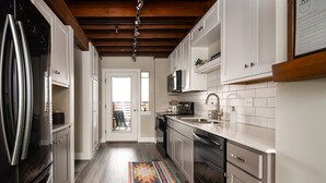 A modern kitchen with white cabinets, stainless steel appliances, and a wooden ceiling. - Teddys Townhouse- New Modern Townhome in Belgrade with lots of natural light! (Belgrade)