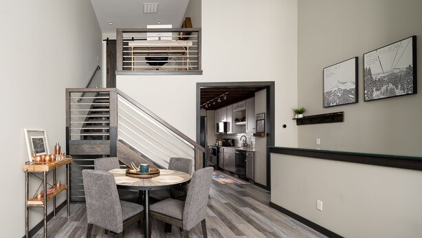A modern kitchen with stainless steel appliances, a dining area with a round table and chairs, and a staircase leading to an upper level. - Teddys Townhouse- New Modern Townhome in Belgrade with lots of natural light! (Belgrade)