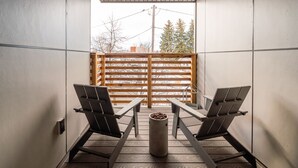 A balcony with two chairs and a table, a wooden fence, and a view of trees and buildings. - Teddys Townhouse- New Modern Townhome in Belgrade with lots of natural light! (Belgrade)