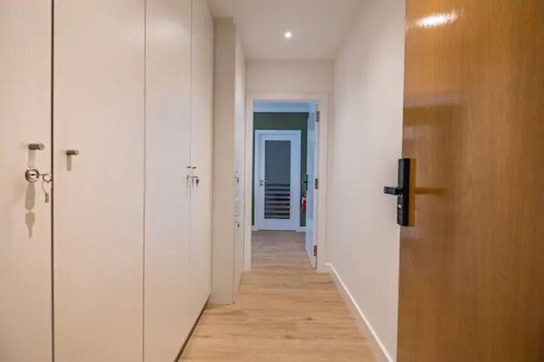 A narrow hallway with wooden flooring and white walls.