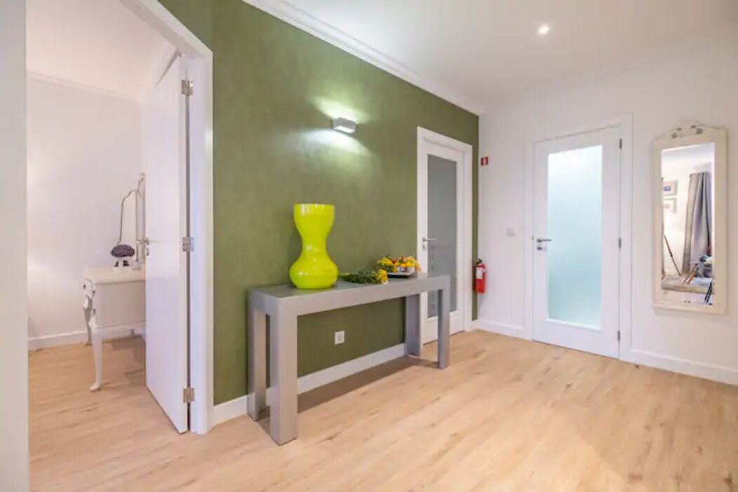 A hallway with a grey console table, a yellow vase, and a small plant.