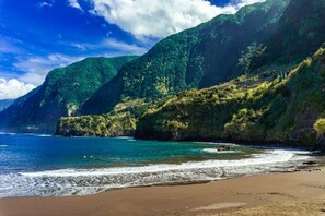 Paisagem costeira com praia, falésias e céu claro.