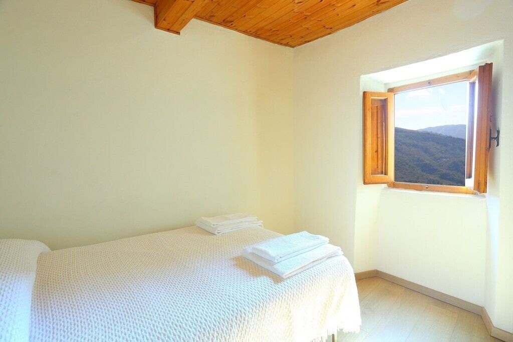 Una habitación con cama, ventana y vista al exterior, además de techo de madera.