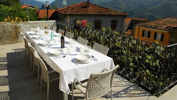 Mesa al aire libre con vista a la montaña, mantel blanco y sillas de mimbre.