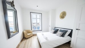 Quarto com cama grande, uma cadeira, janela e espelho.