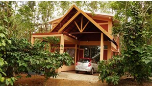 A small, single-story building with a sloped roof and a car parked in front.