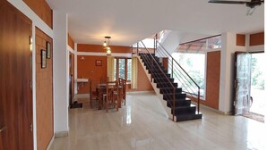 A spacious living area with a polished floor, a staircase with metal railings, and a dining area with wooden furniture.
