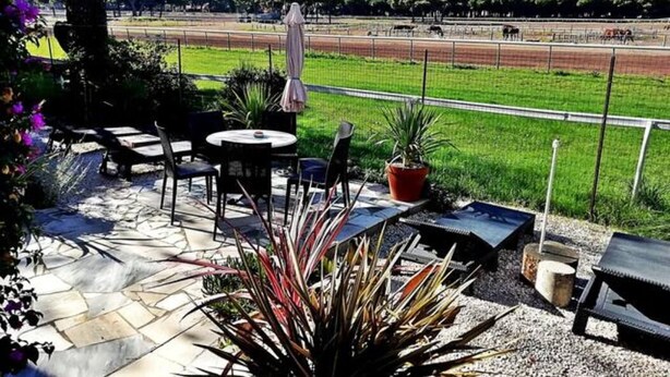 Une terrasse extérieure avec des sièges, un barbecue et une vue sur un circuit de course.