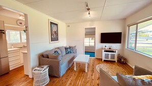 Um espaço compacto com cozinha compacta, um sofá, uma mesa de centro e uma televisão.