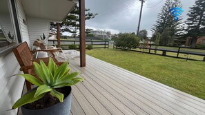 A wooden deck with outdoor furniture and a potted plant. - Bombora – Across From The Beach (Callala Beach)