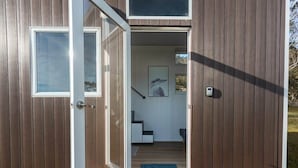 A wooden cabin with a sliding glass door, a staircase, and a blue mat at the entrance.