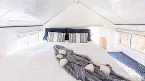 A bedroom with a large bed, a window, and a ceiling fan.
