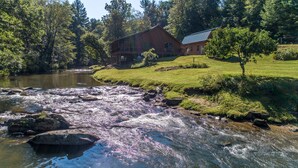 Uitzicht op een rivier met een houten hut en een gazon.