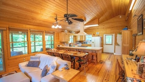 Een gezellig interieur van een blokhut met een eethoek, keuken en een woonkamer met een bank en een salontafel.